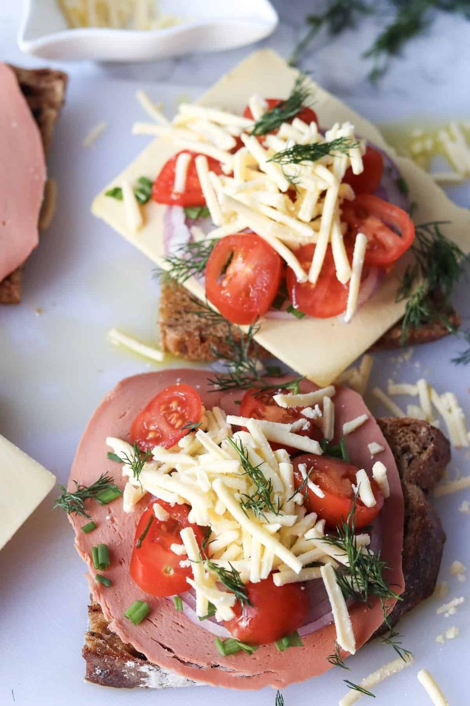 Vegan dill-tomato sandwiches on a white plate.