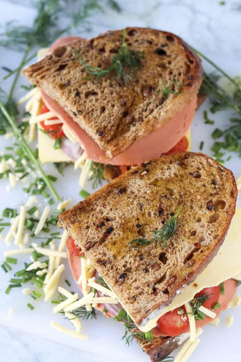 A vegan sandwich with tomatoes and cheese on a cutting board.