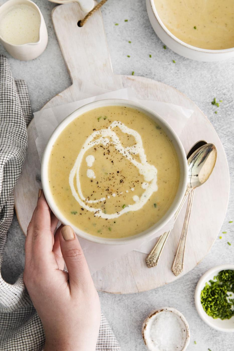 a bowl of cheddar soup with a swirl of cream and crack of pepper on top