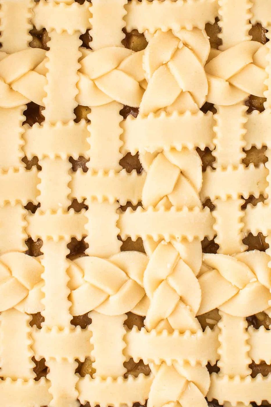 Unbaked pie with a lattice crust, featuring crimped and braided pastry strips in a decorative pattern—perfect for transforming into delightful Apple Pie Bars.
