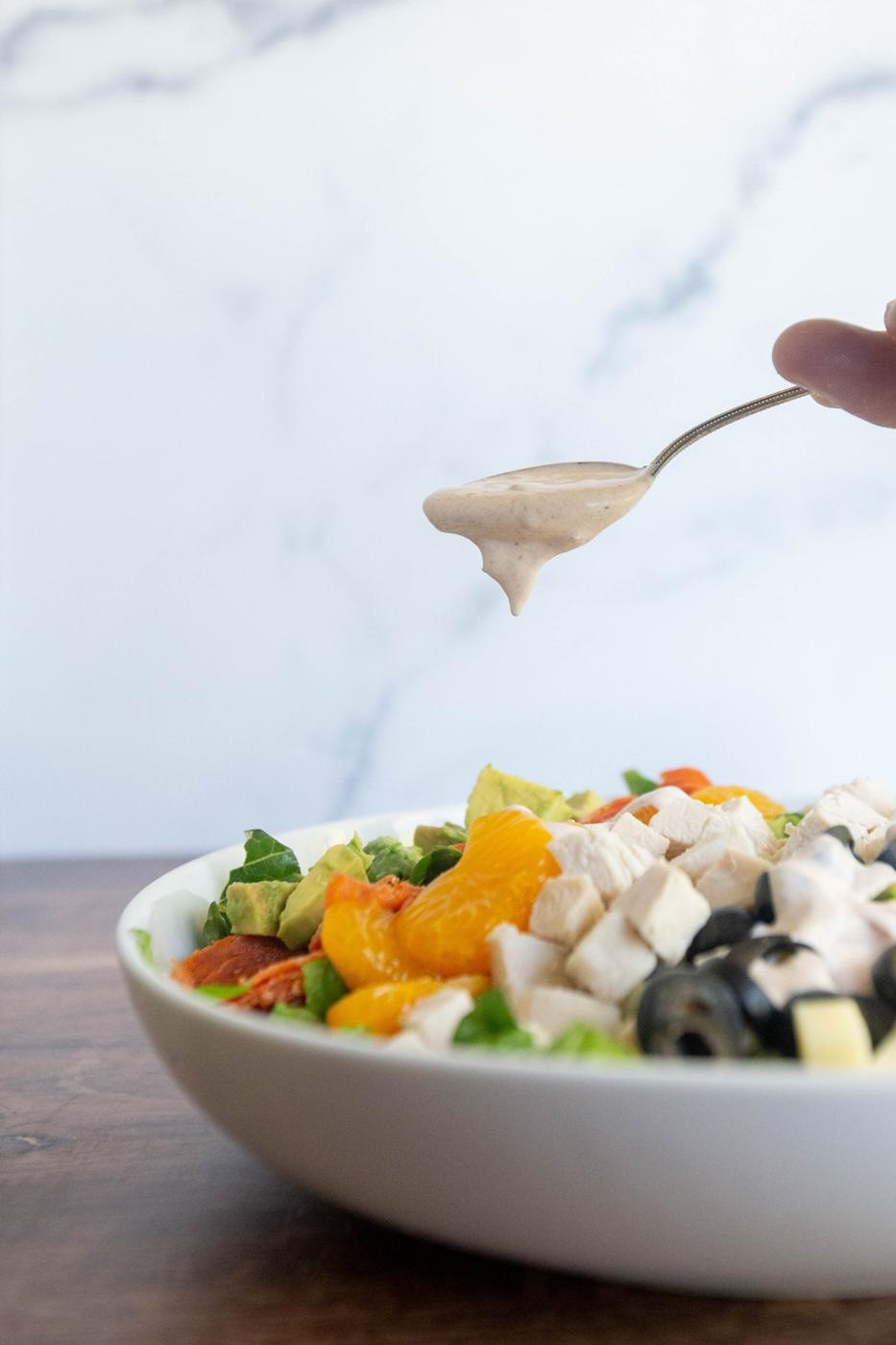 picture of a spoon adding dressing to a salad bowl