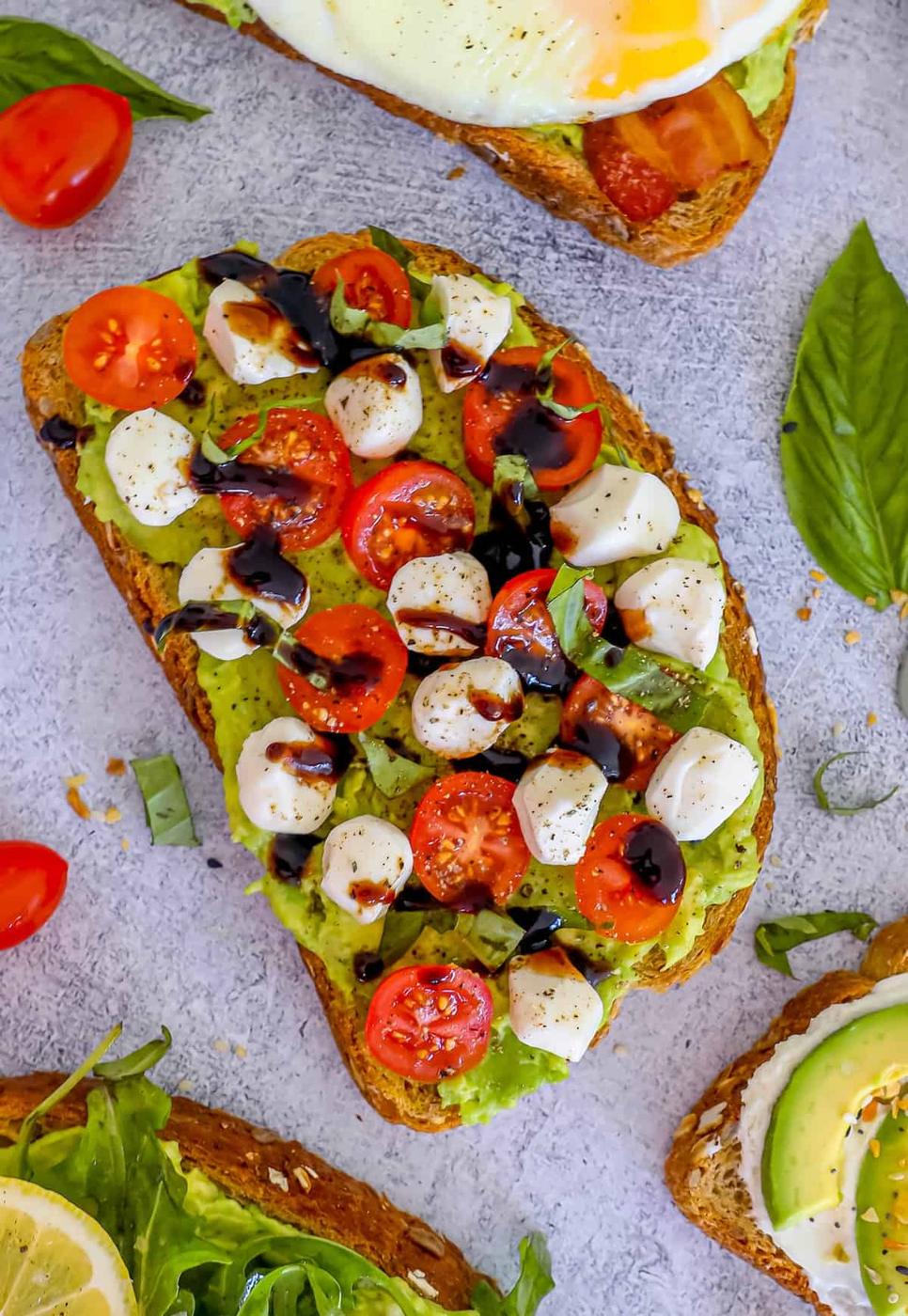 A toast with tomatoes, avocado, and an egg on it.