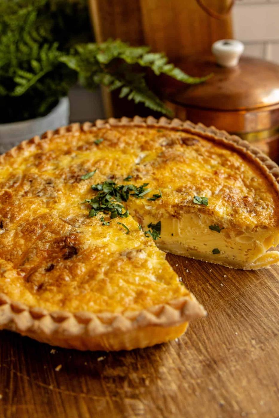 A bacon and cheese quiche with a missing slice.
