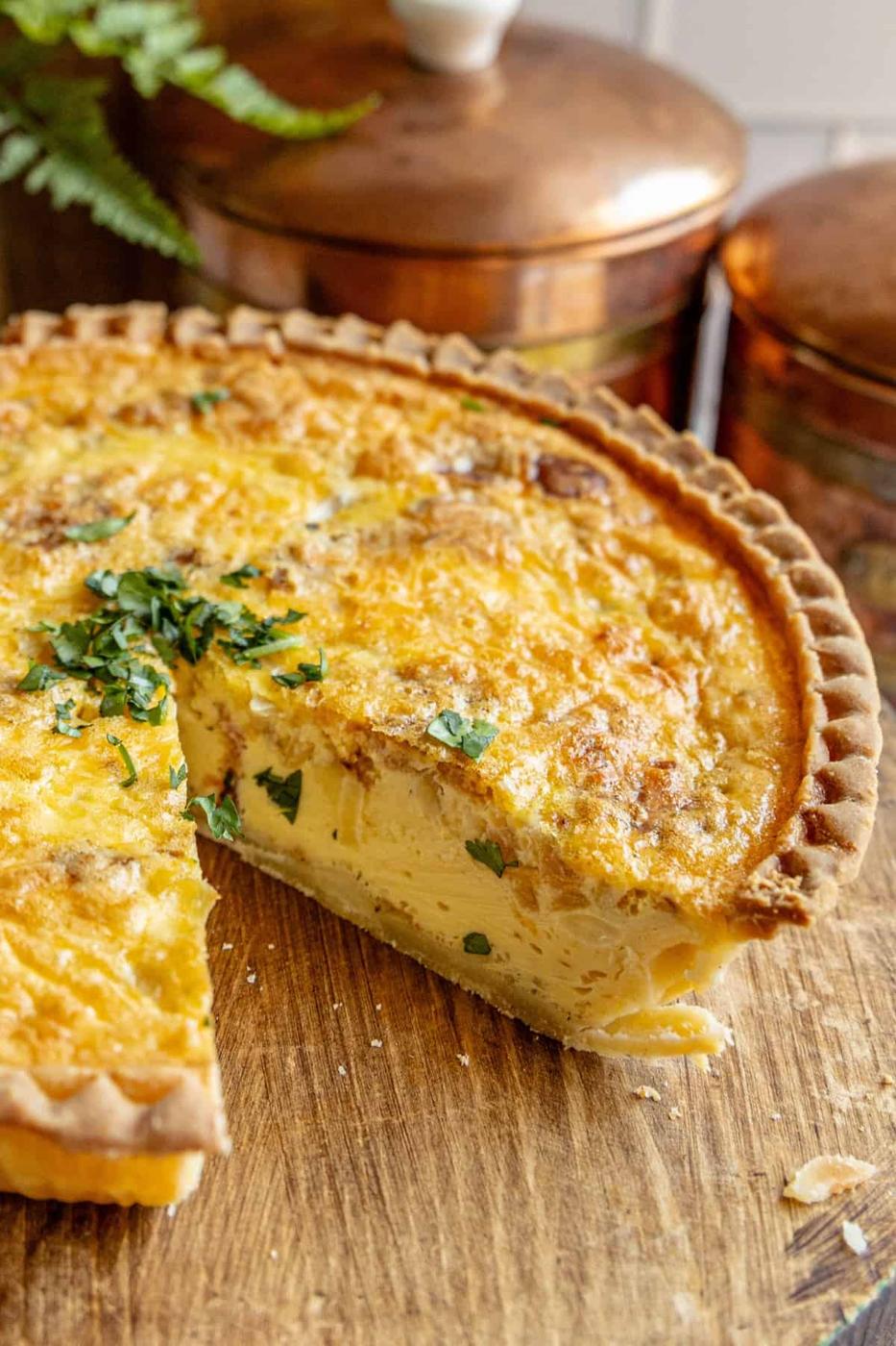 A bacon quiche with a slice missing.