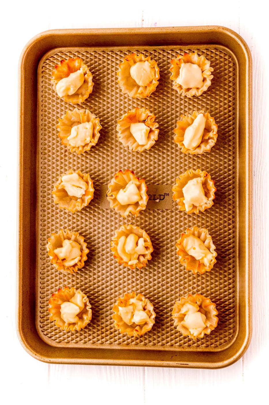 A tray full of small appetizers, including bacon wrapped raspberry cheese bites.