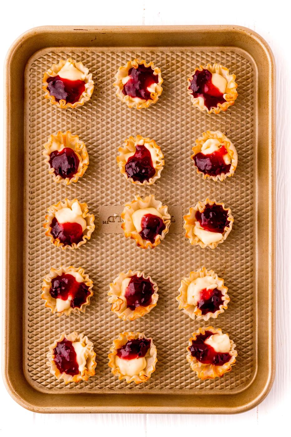 A tray of mini tarts with cranberry sauce on it. (No keywords added)