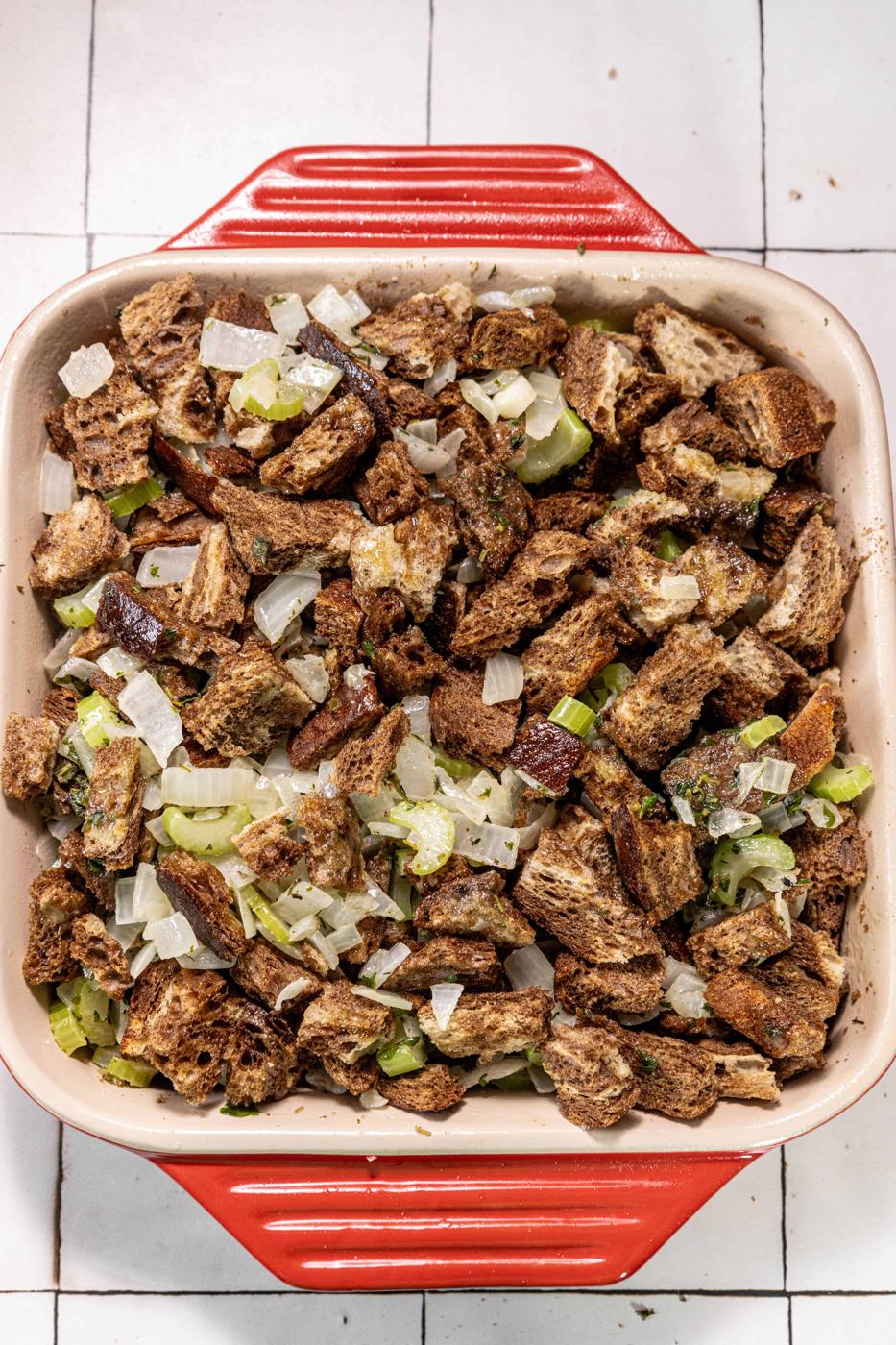A red baking dish filled with bacon and vegetables.
