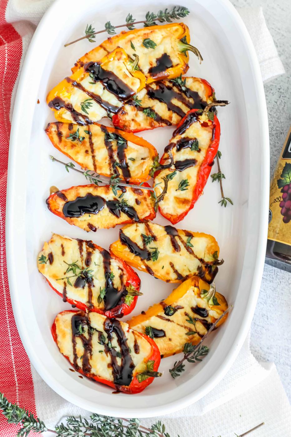 Baked peppers with goat cheese and herbs in a white dish.