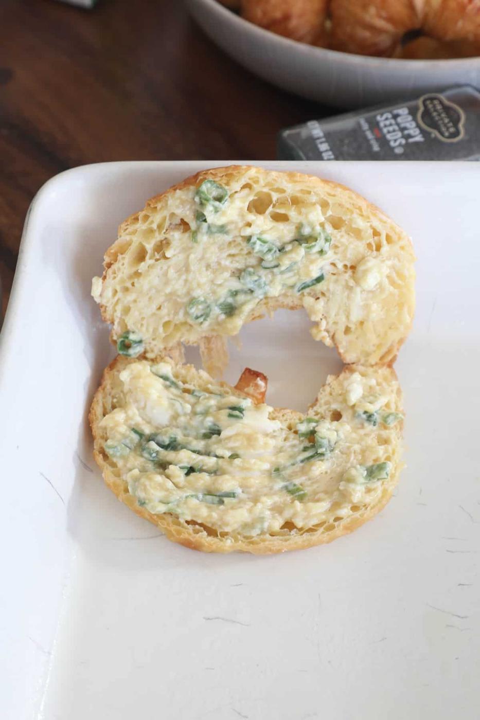 A white plate with a bagel with spinach on it.