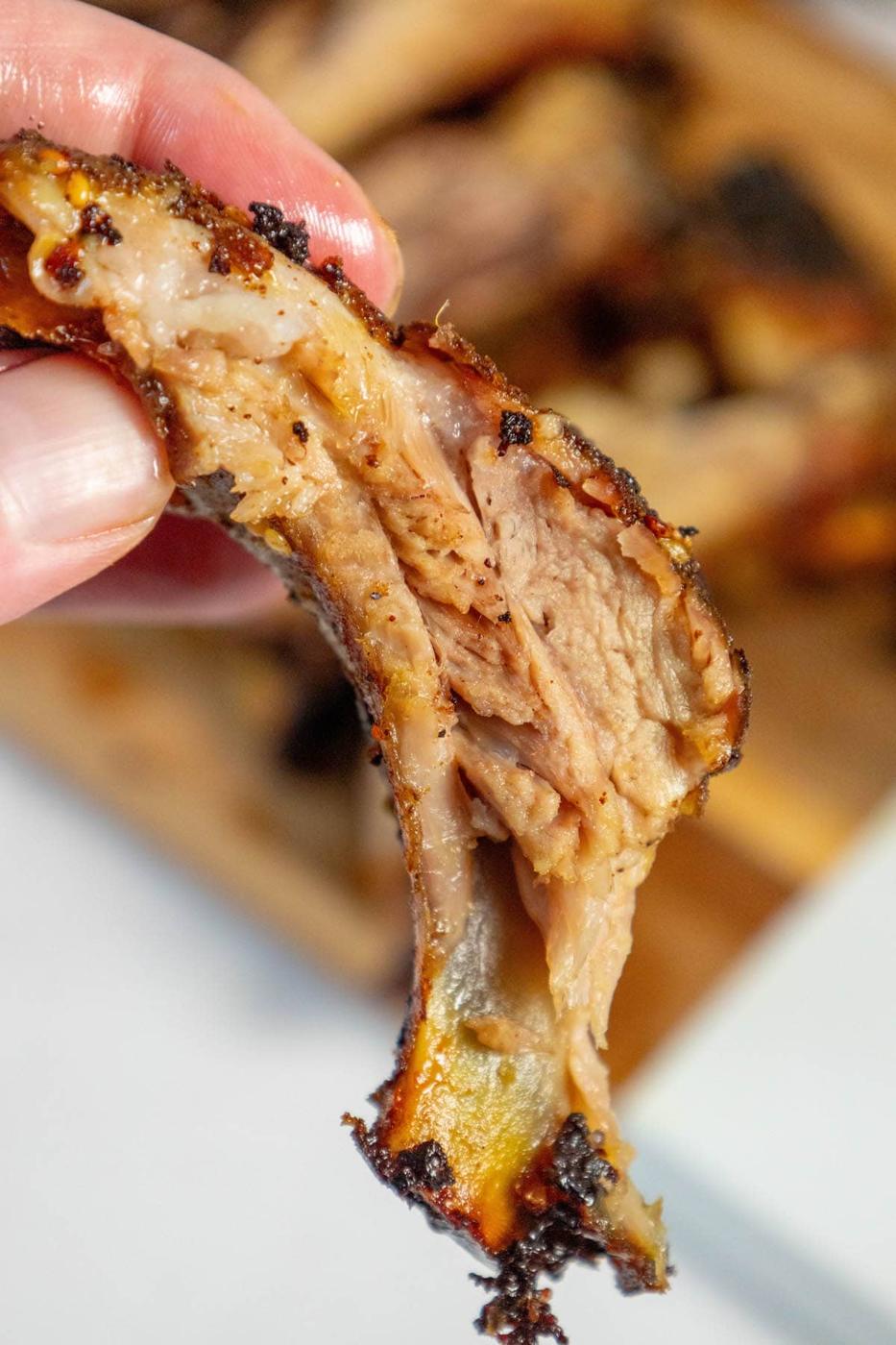 a hand holding a rib baked with shawarma rub