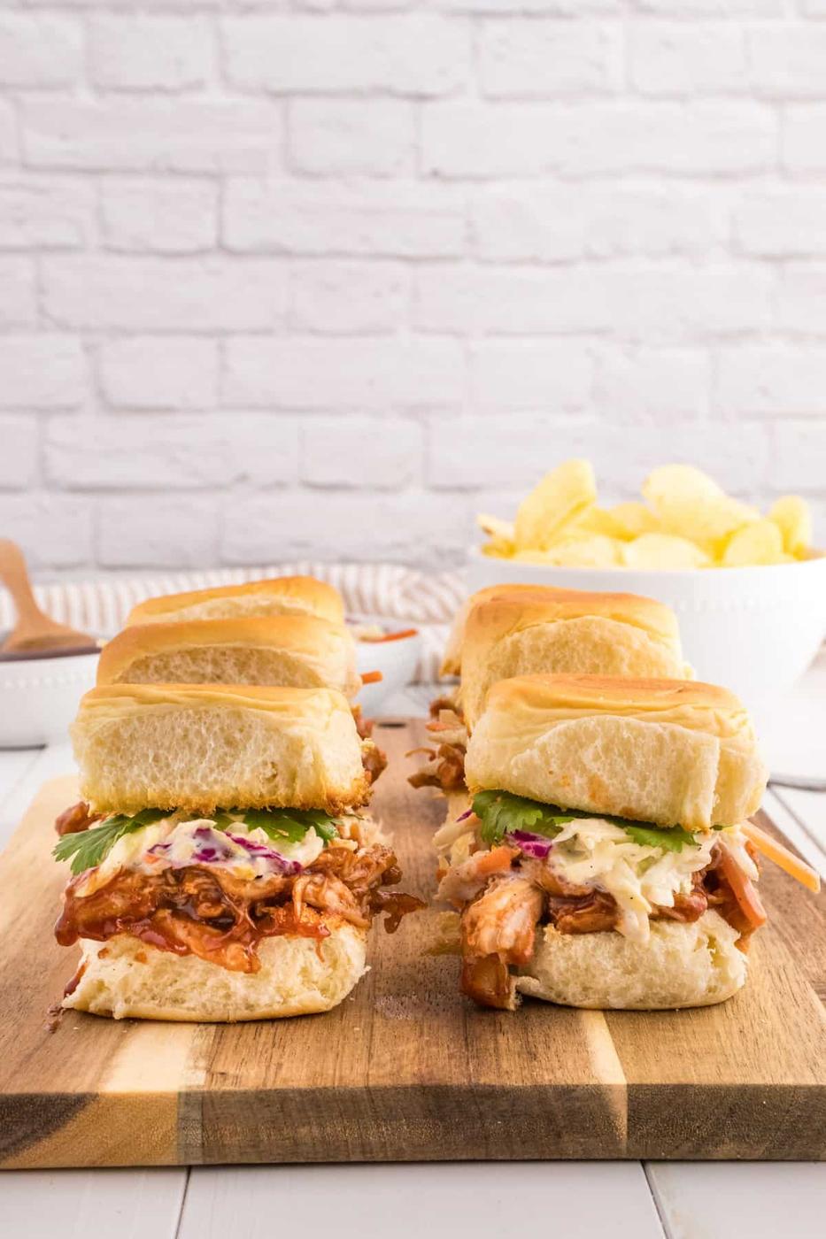 BBQ pulled pork sliders on a wooden cutting board.