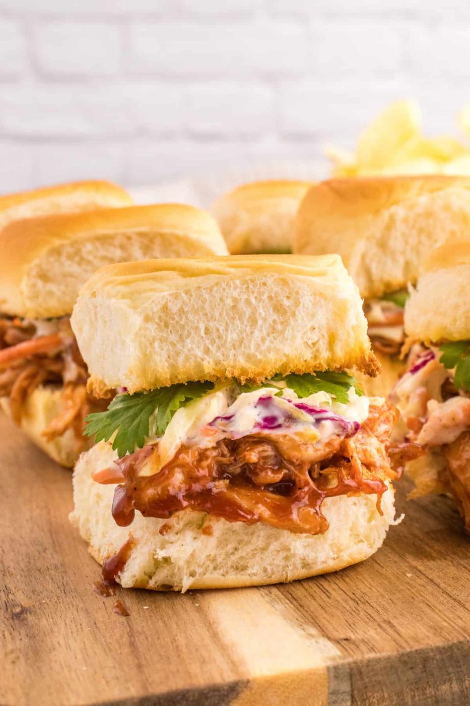 BBQ pulled pork sliders on a wooden cutting board.