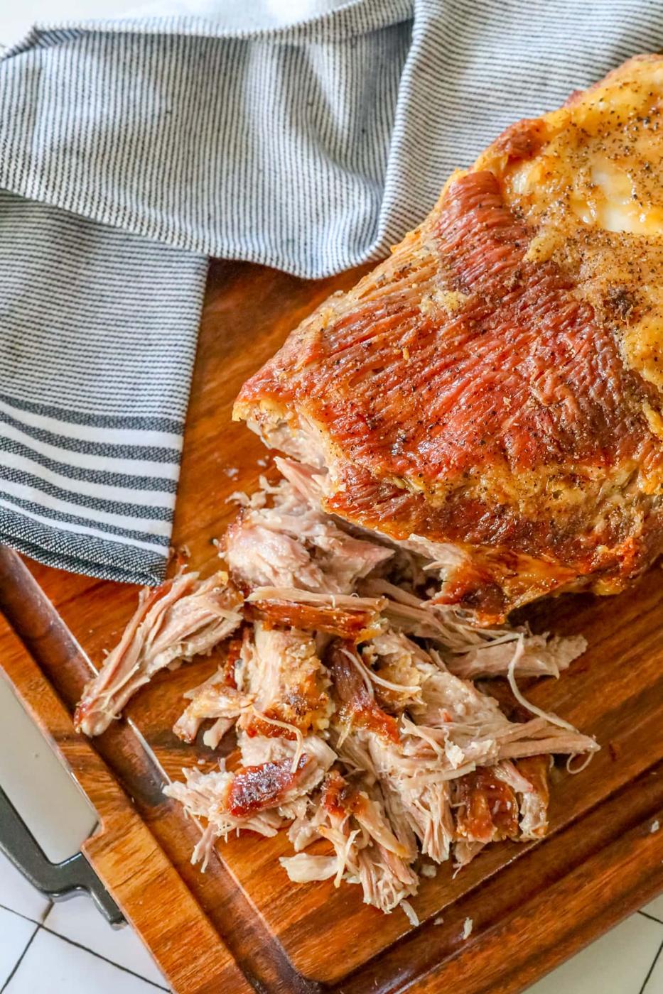 A savory pulled pork on a rustic wooden cutting board.