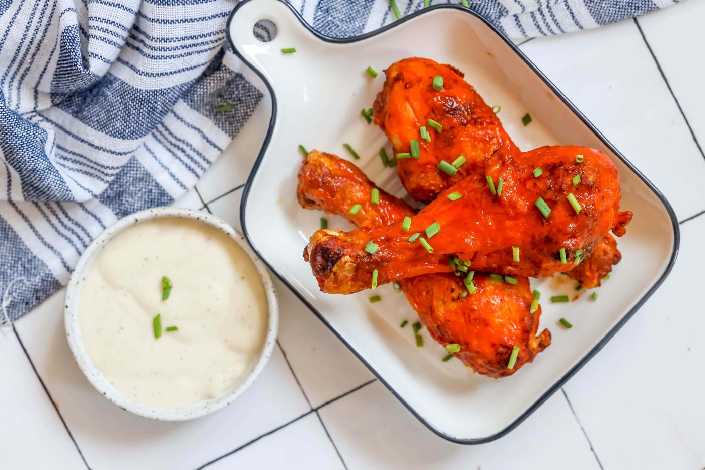 chicken drumsticks with red buffalo sauce on them dip on the side