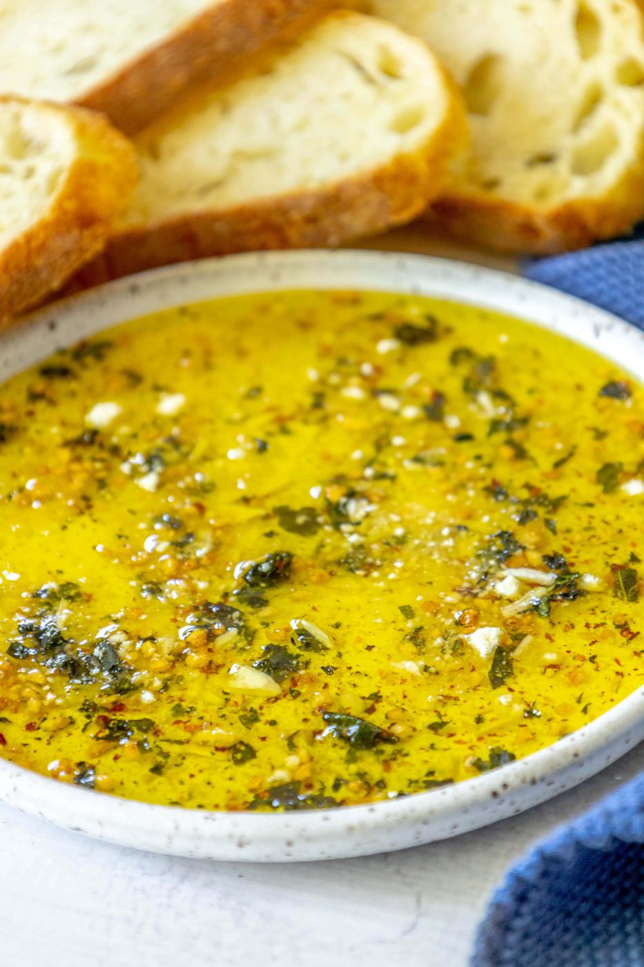 a slice of bread next to a bowl full of olive oil bread dip