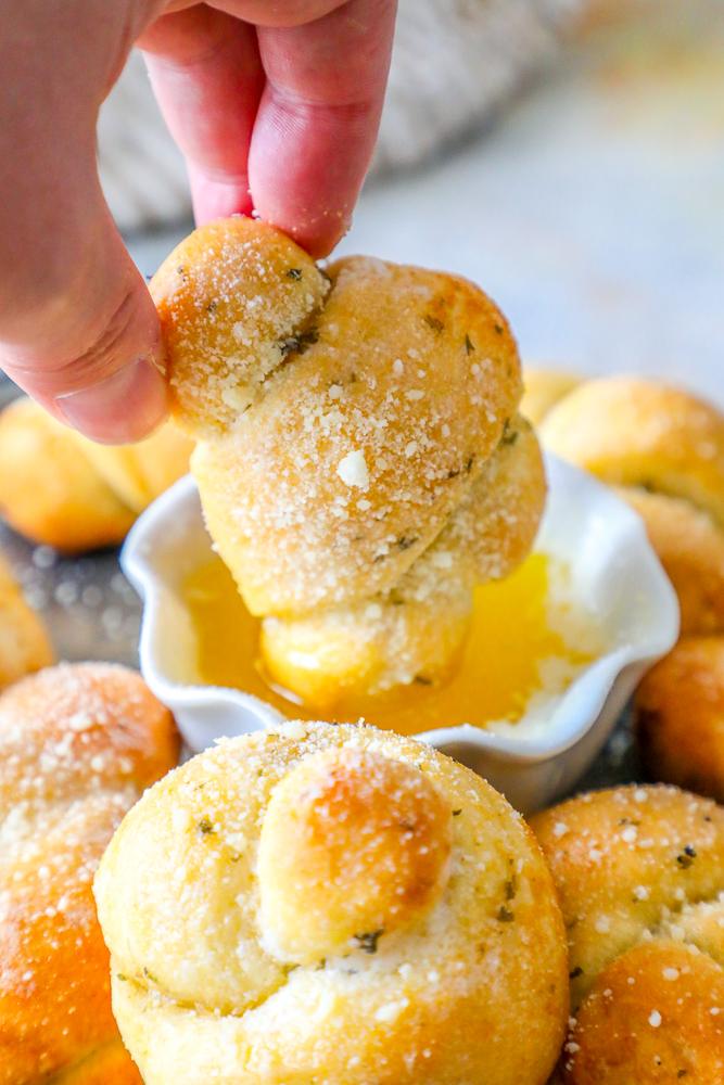 a garlic knot being dipped into melted butter