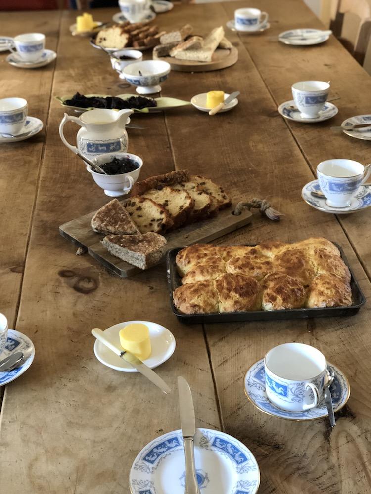cups, saucers, biscuits, bread, and jam on the table