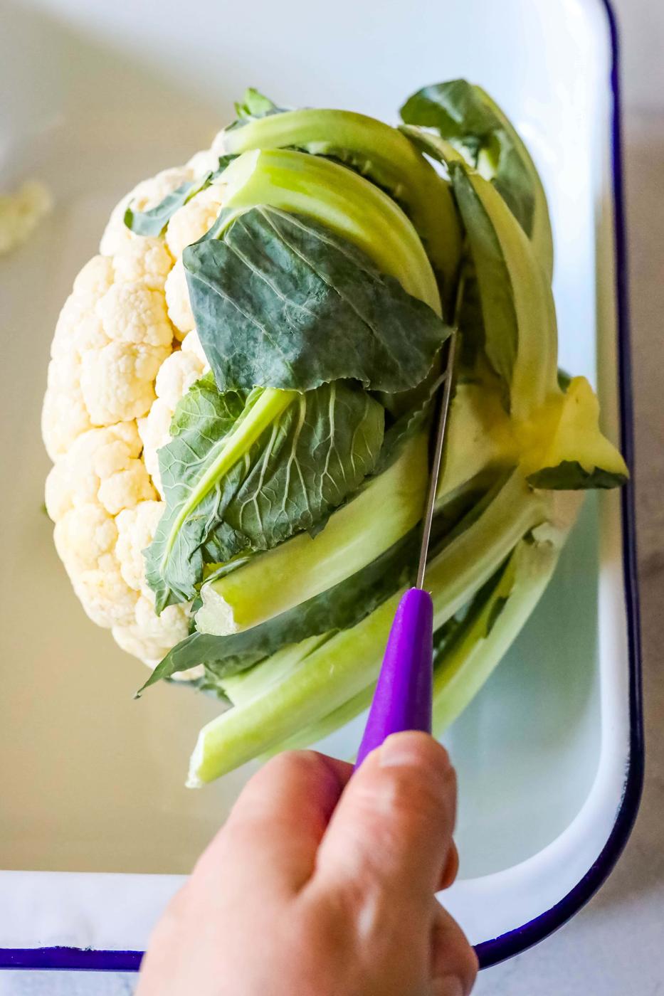 A person preparing an easy keto roasted cauliflower dish in a baking dish.