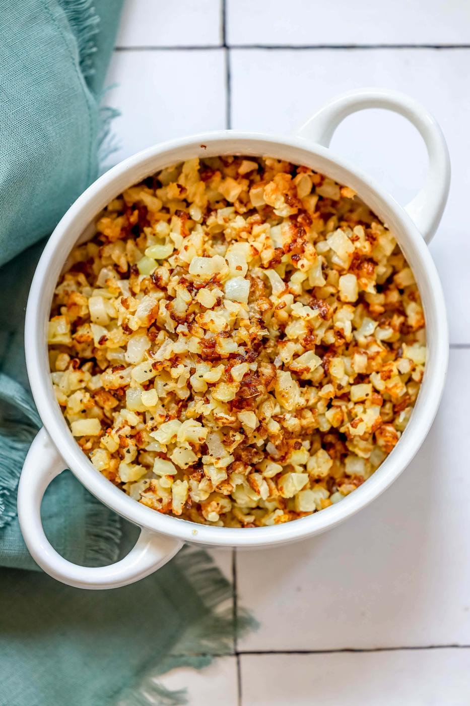 browned cauliflower rice in a white bowl.