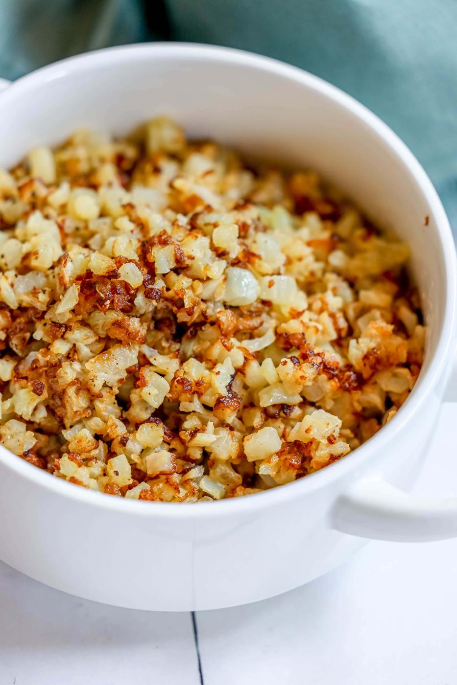 browned cauliflower rice in a white bowl.