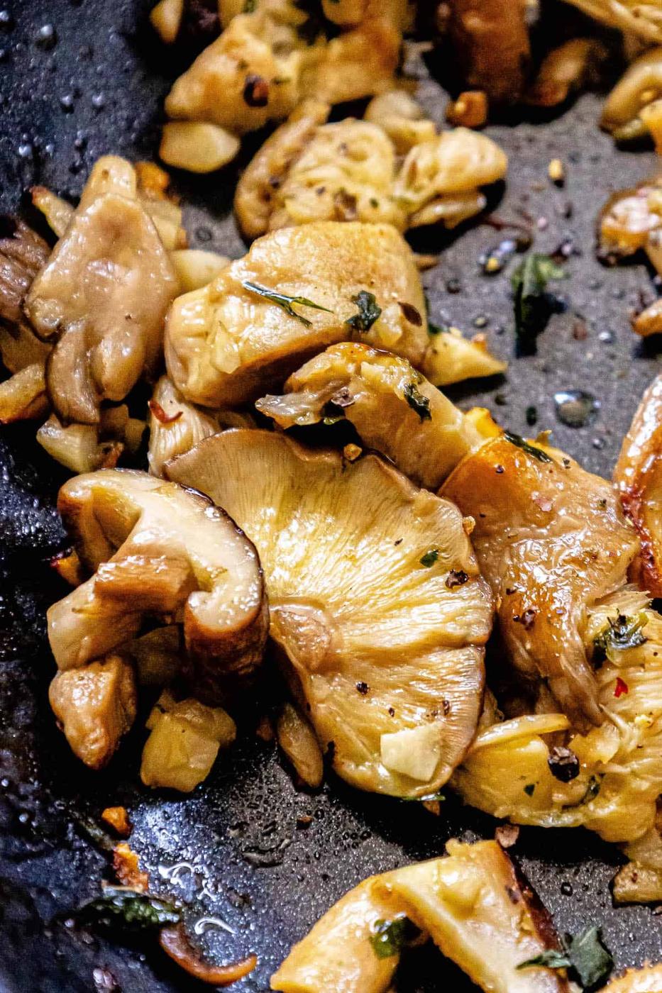 A frying pan with mushrooms and herbs on it.