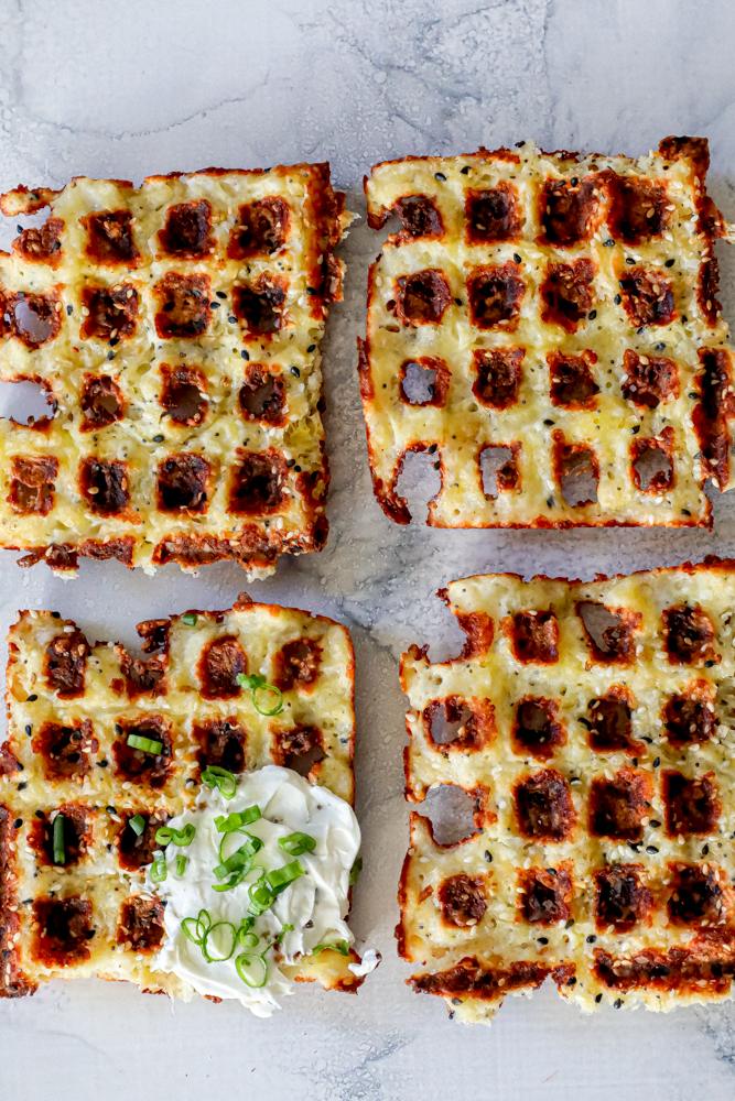 A plate of keto everything chaffles topped with sour cream and chives.
