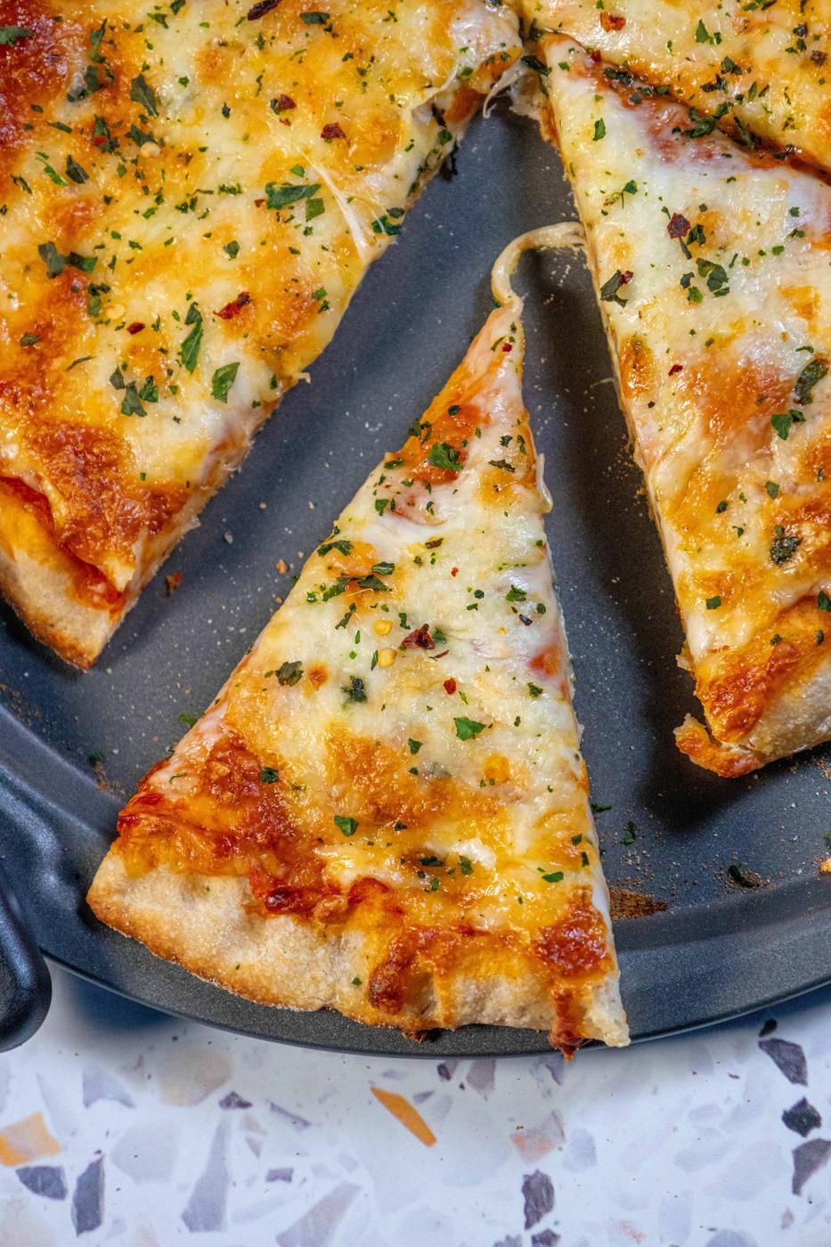 A slice of pizza on a plate with the best pizza dough.