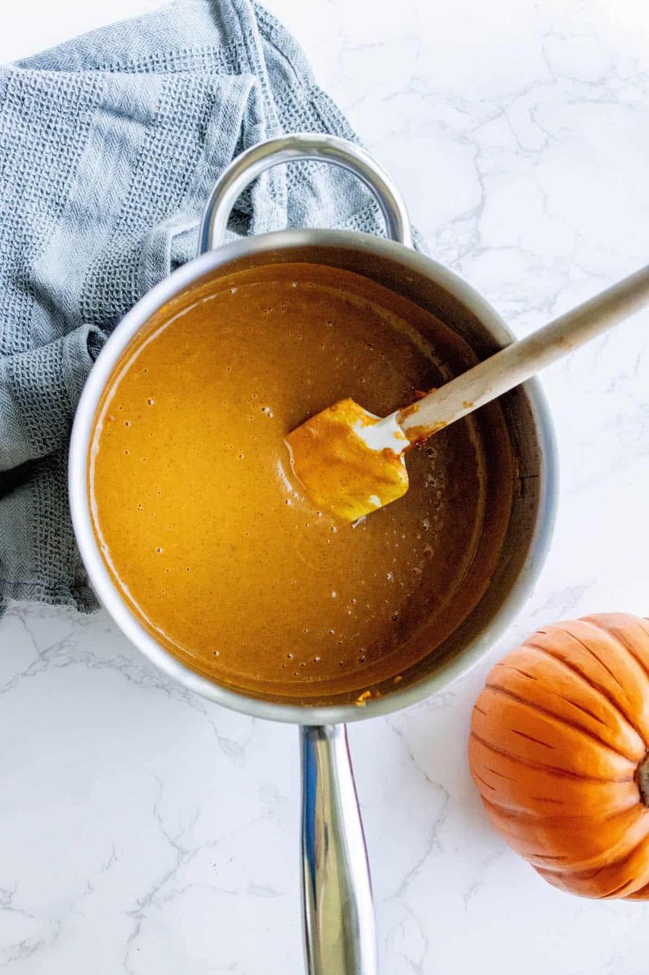 A pot of pumpkin pie puree with a spoon in it.