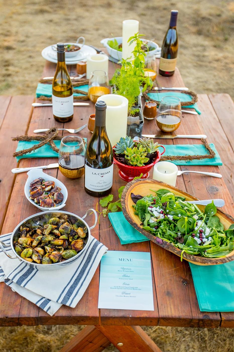 table set up with whine, brussels sprouts, and salad.