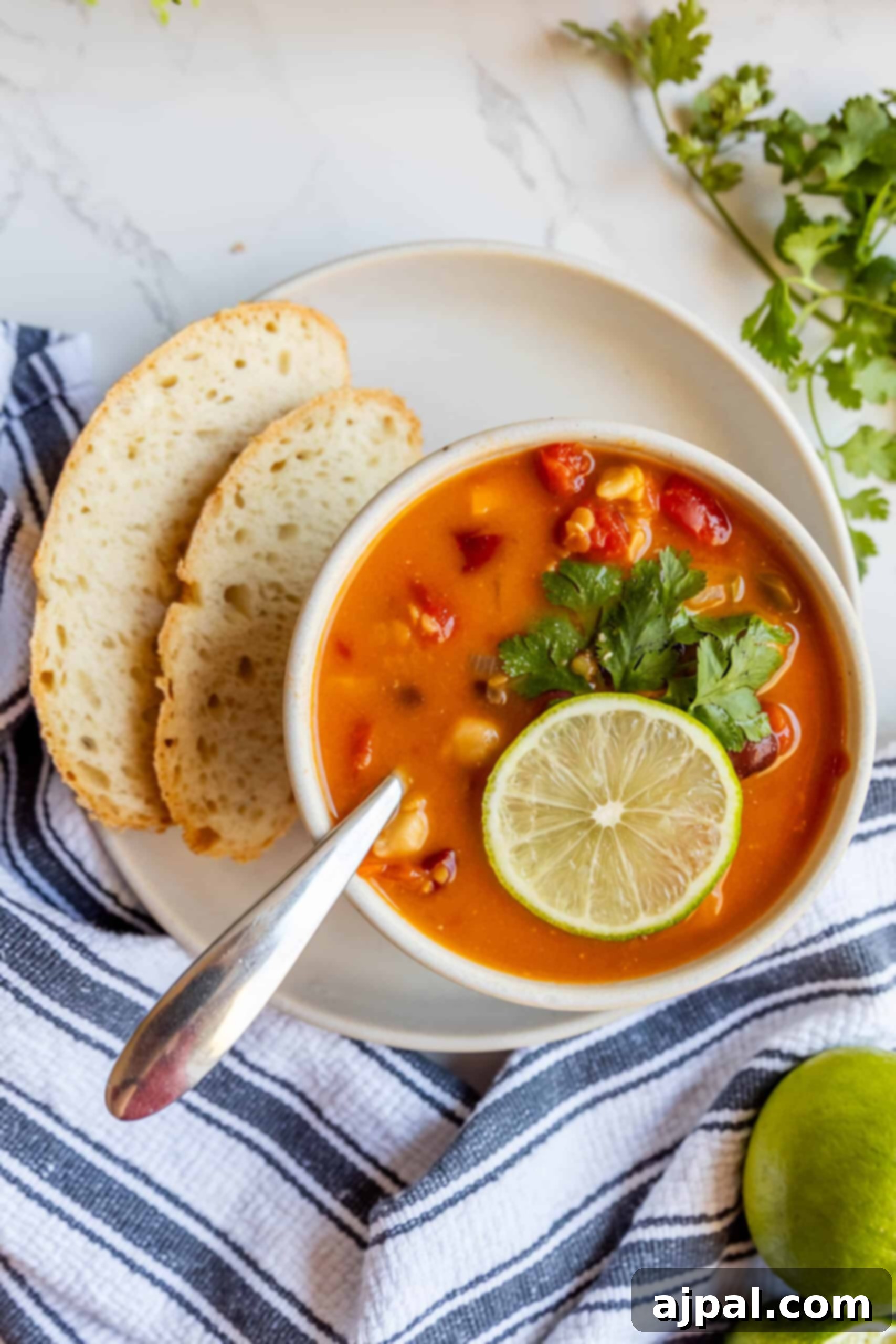 Two bowls of Vegan Thai Curry Soup, garnished with fresh lime and chili, ready to be served.