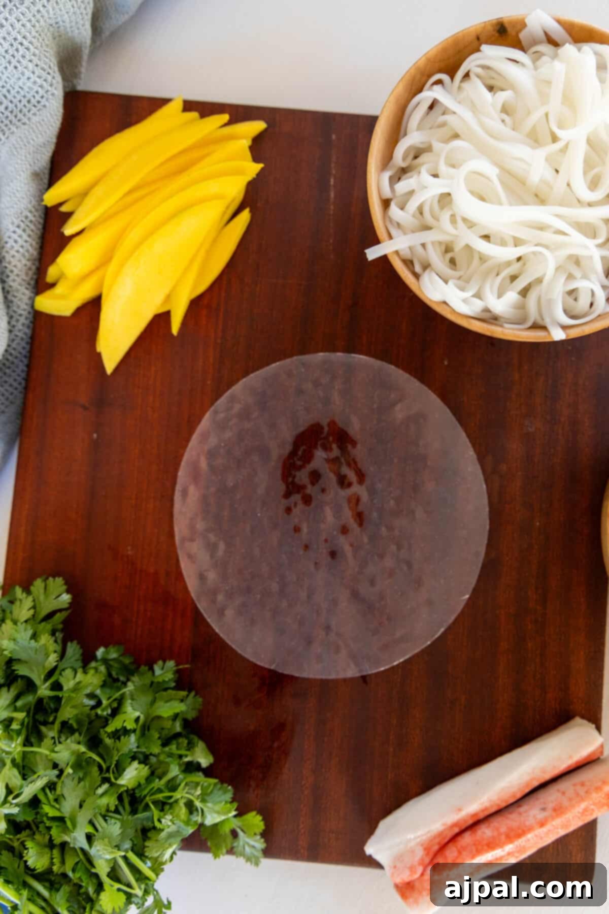 A cutting board with crab spring rolls and ingredients.