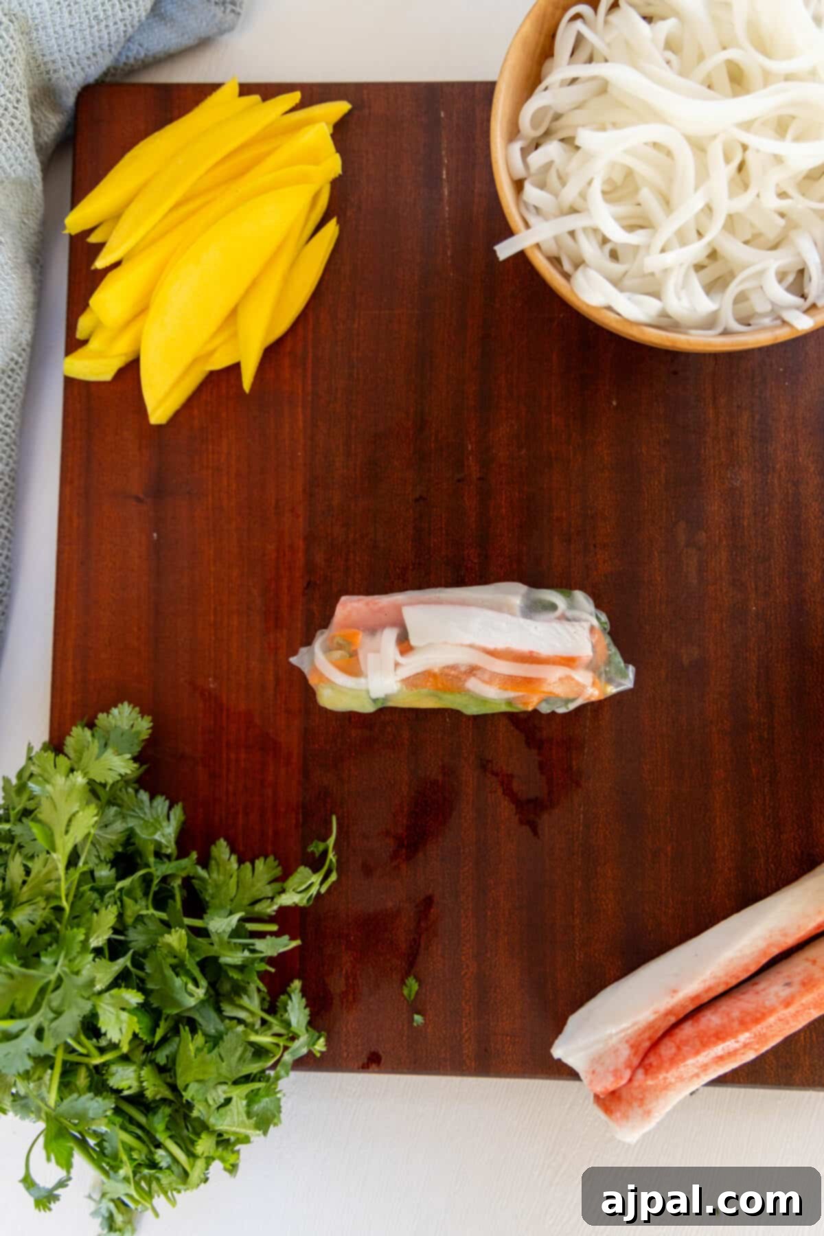 A cutting board of ingredients for a Vietnamese spring roll featuring crab.