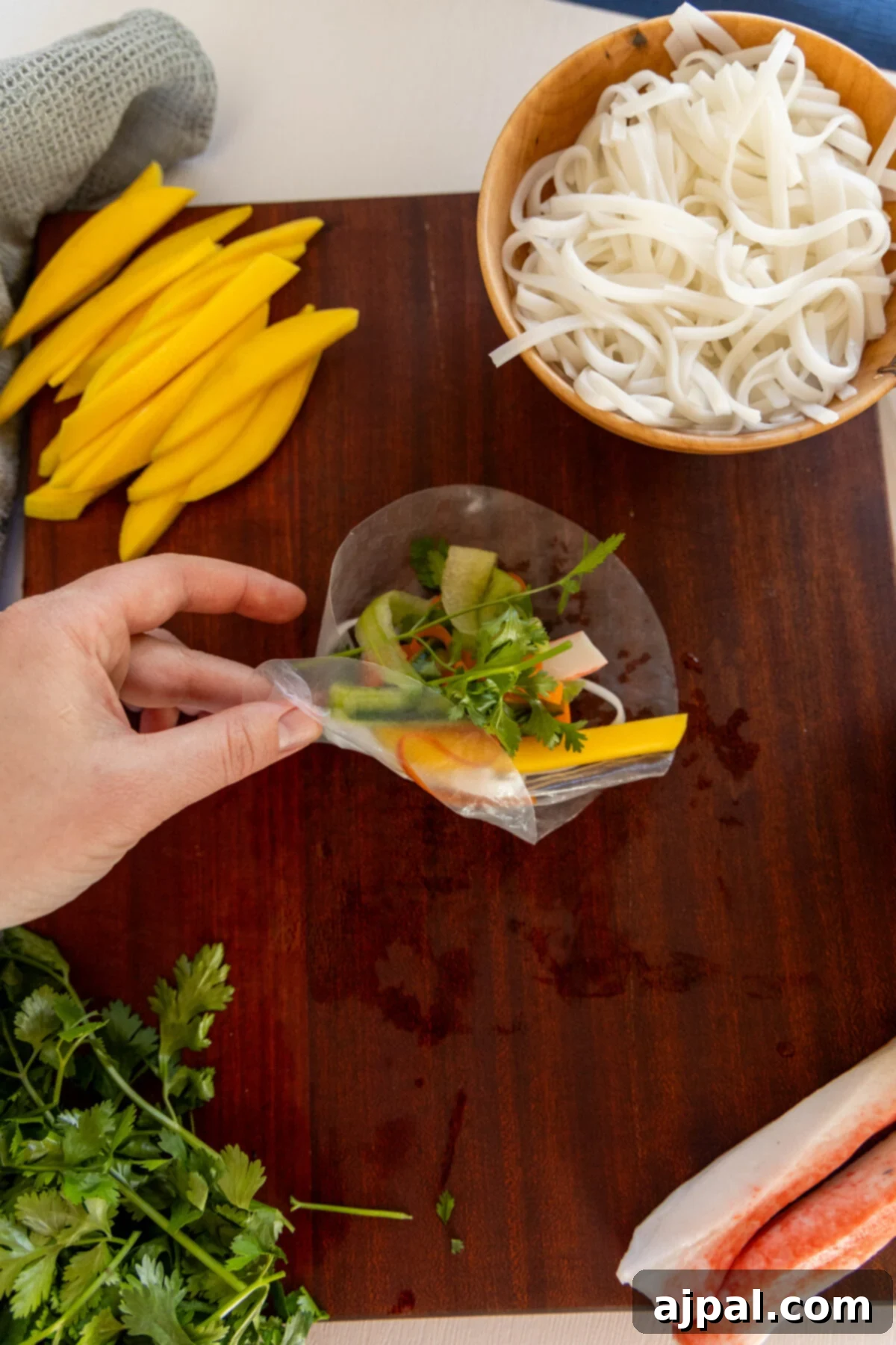 A person is preparing ingredients for crab spring rolls on a cutting board.