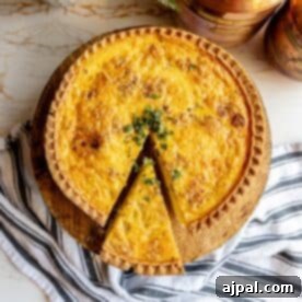 A beautifully baked quiche with a slice removed, revealing a rich filling.