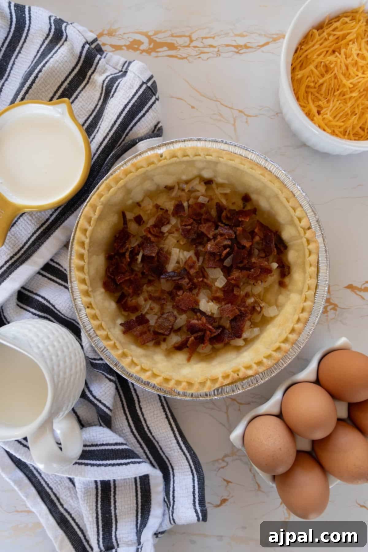 A pie with bacon and cheese in a pie pan, prior to baking.