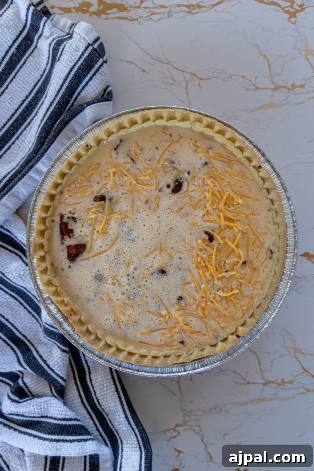 A baked quiche with bacon and cheese, cooling on a table.