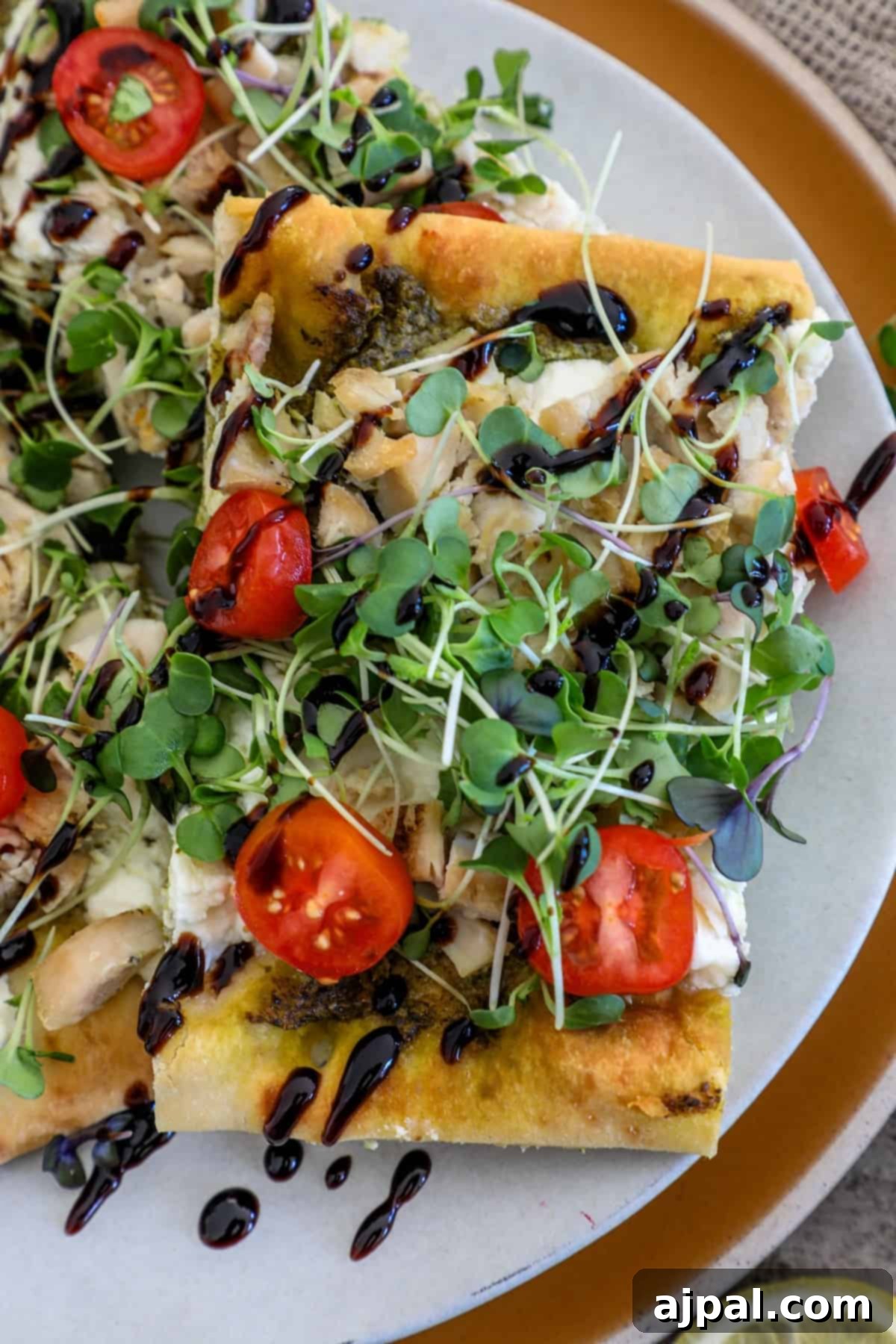 Artisan Pesto Chicken Flatbread 2 A beautifully presented flatbread chicken pesto pizza, garnished with fresh lemony arugula and a balsamic glaze swirl, ready to be enjoyed.