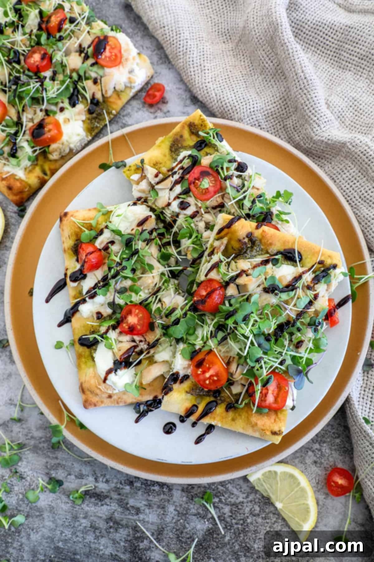 Artisan Pesto Chicken Flatbread 11 A beautifully presented flatbread chicken pesto pizza, garnished with fresh basil and cherry tomatoes, resting on a wooden table.