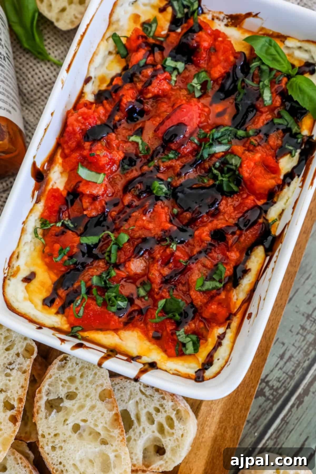A beautifully arranged dish of tomato and basil dip, presented on a natural wooden cutting board, invitingly garnished for a fresh appetizer.
