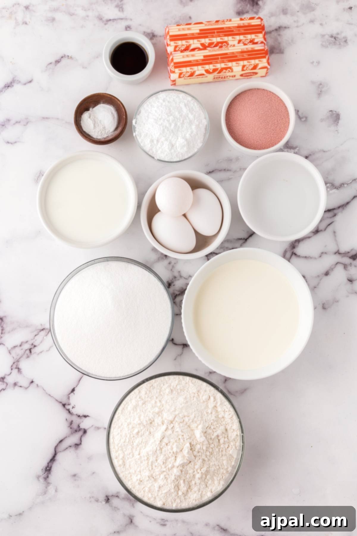 An array of fresh baking ingredients, including flour, butter, sugar, and raspberries, arranged on a marble countertop, ready for baking a delicious cake.