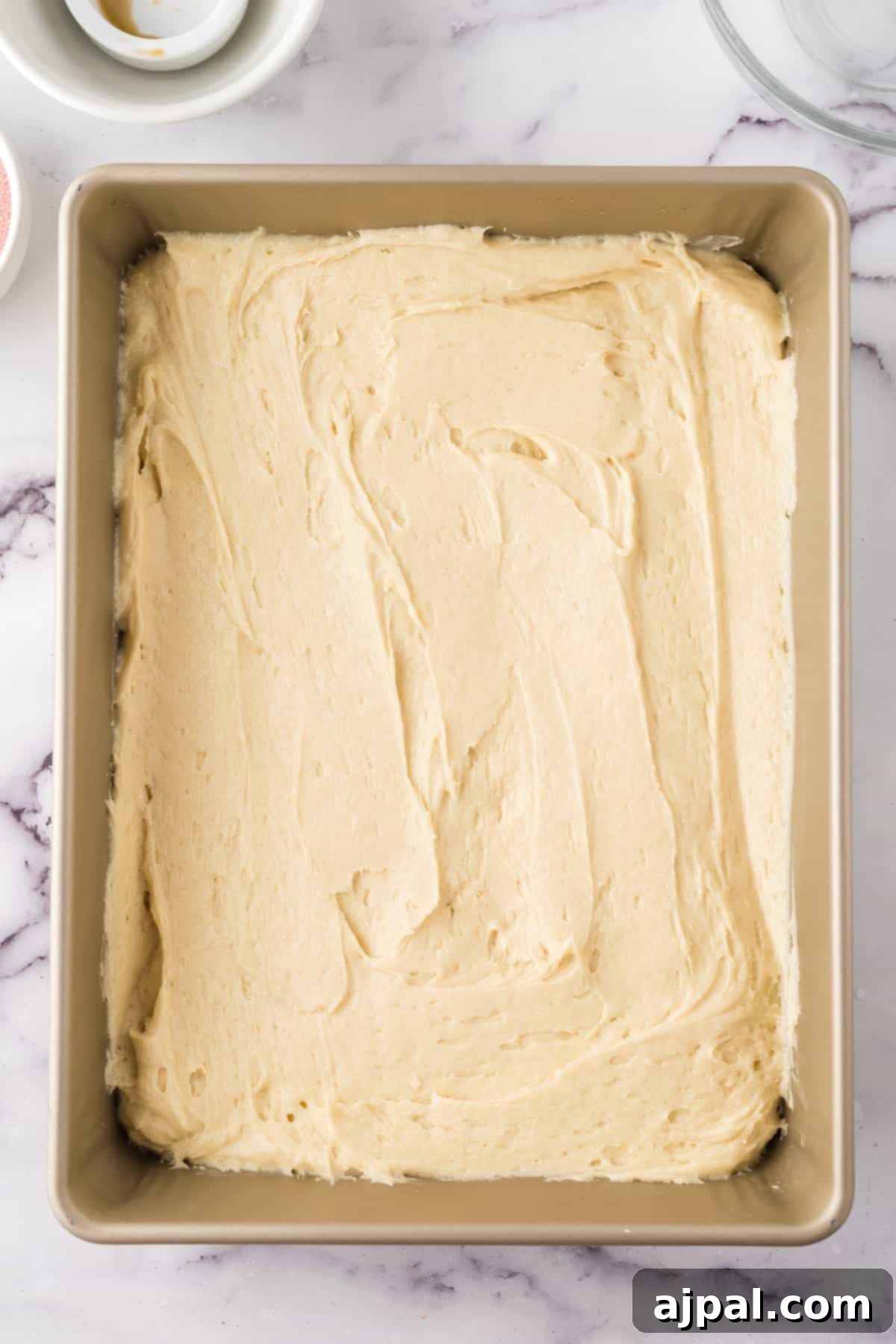 A pristine white baking pan holds a partially baked raspberry sheet cake, its edges lightly golden and the center still soft, promising a delicious treat.