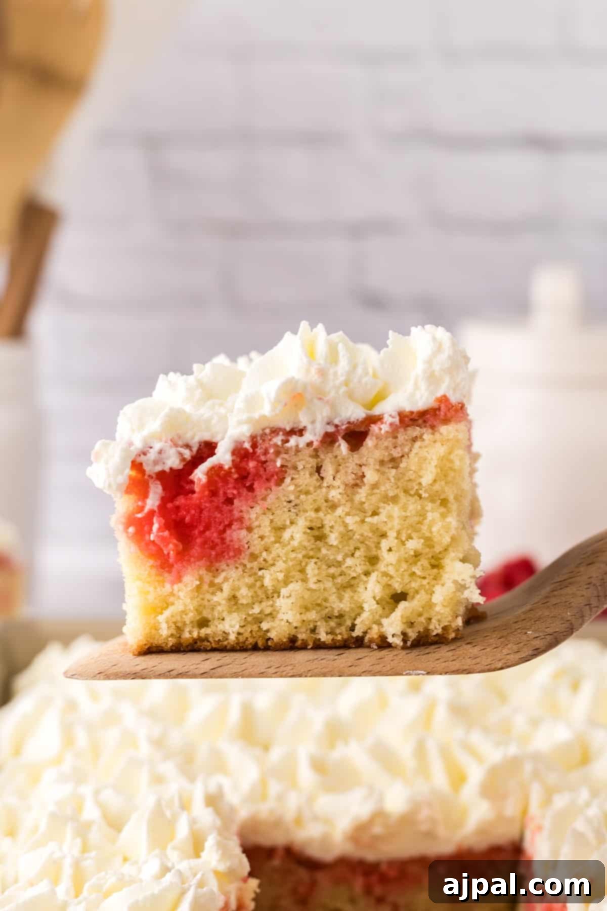 A freshly baked sheet cake, richly topped with creamy frosting and adorned with whole fresh raspberries, creating a vibrant and tempting dessert.
