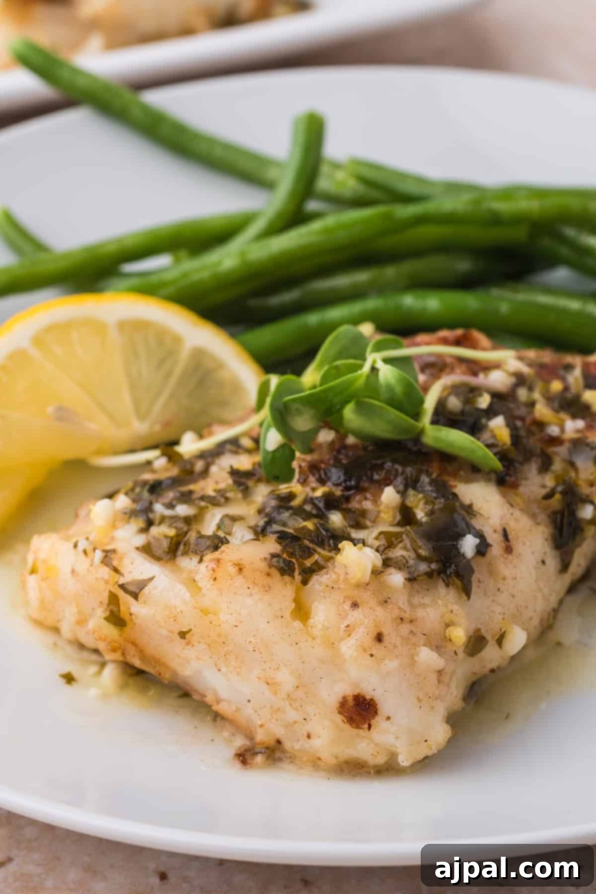 Golden Pan-Seared Cod 2 A plate with beautifully pan-fried cod fillets, vibrant green beans, and a wedge of fresh lemon, ready to be enjoyed as a healthy and delicious meal.