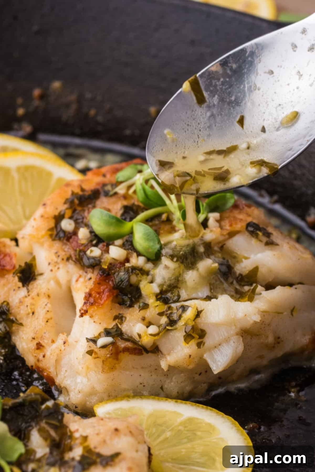 Golden Pan-Seared Cod 13 A cast iron skillet filled with cooking fish fillets, adorned with vibrant lemon slices and fresh herbs, illustrating the final stages of the pan-frying process and creating an aromatic dish.