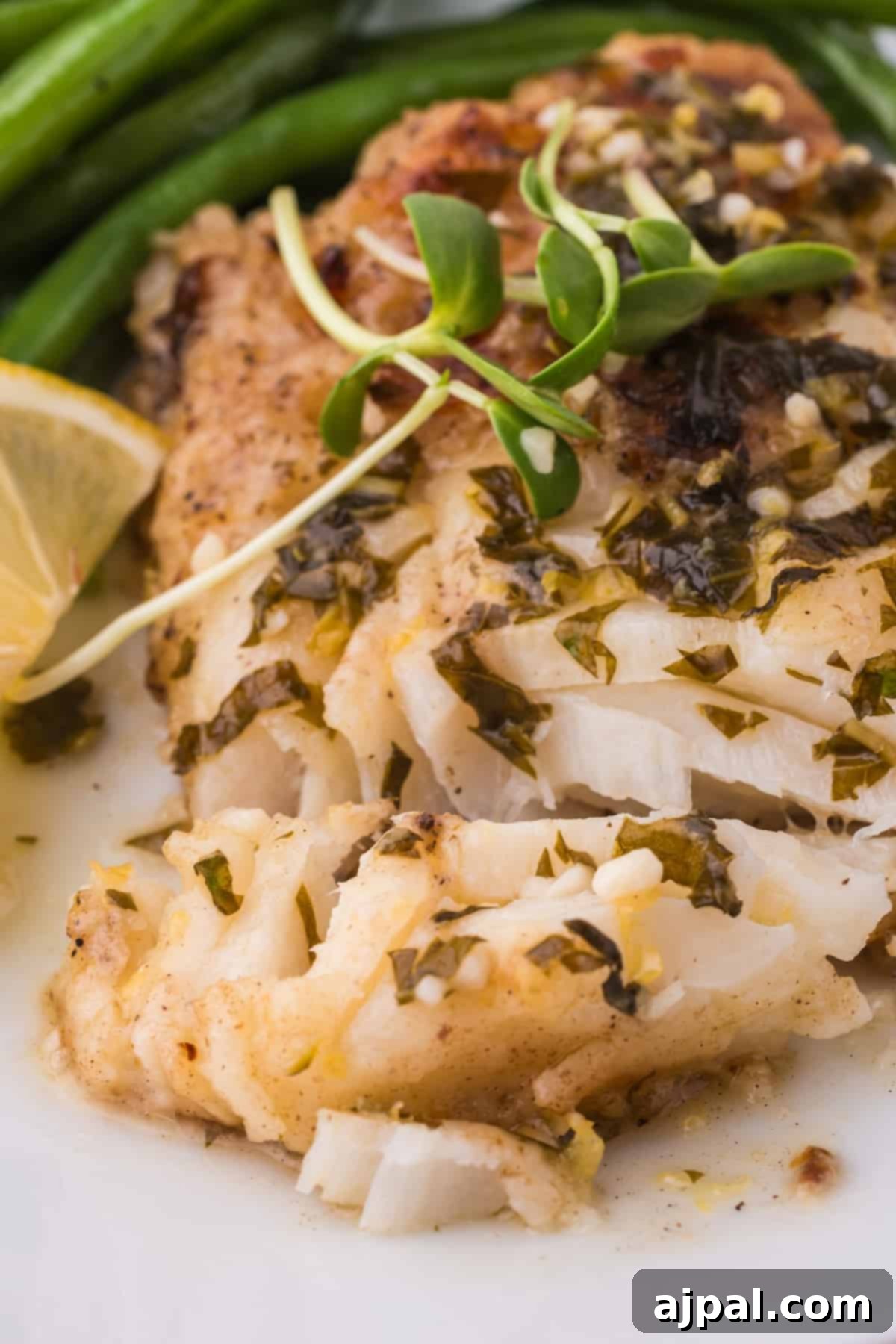Golden Pan-Seared Cod 3 Close-up of a pan-fried cod fillet with a sprinkle of fresh lemon zest and herbs on a clean white plate, highlighting its crispy texture and delicious garnish.