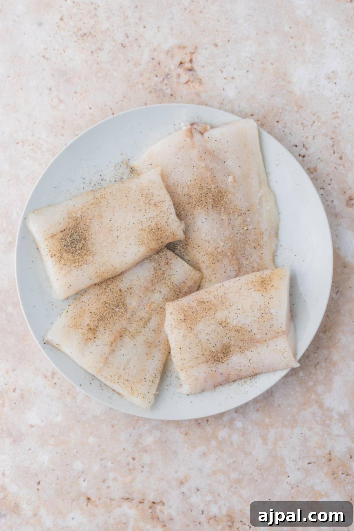 Golden Pan-Seared Cod 6 Seasoned cod fillets coated lightly with all-purpose flour on a plate, ready for pan-frying, ensuring a crispy crust.