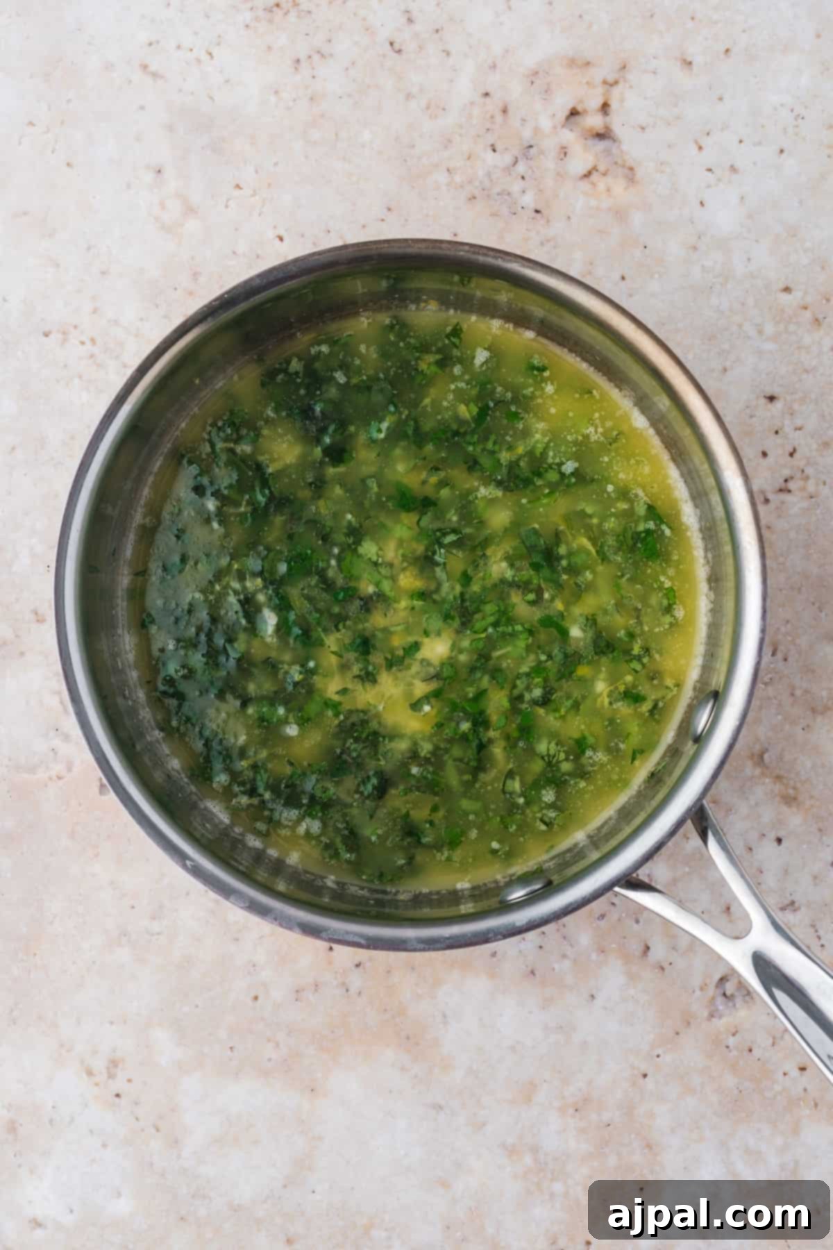 Golden Pan-Seared Cod 8 The lemon-garlic-herb butter sauce simmering in a small saucepan, fragrant and ready for the cod, with vibrant green herbs visible.