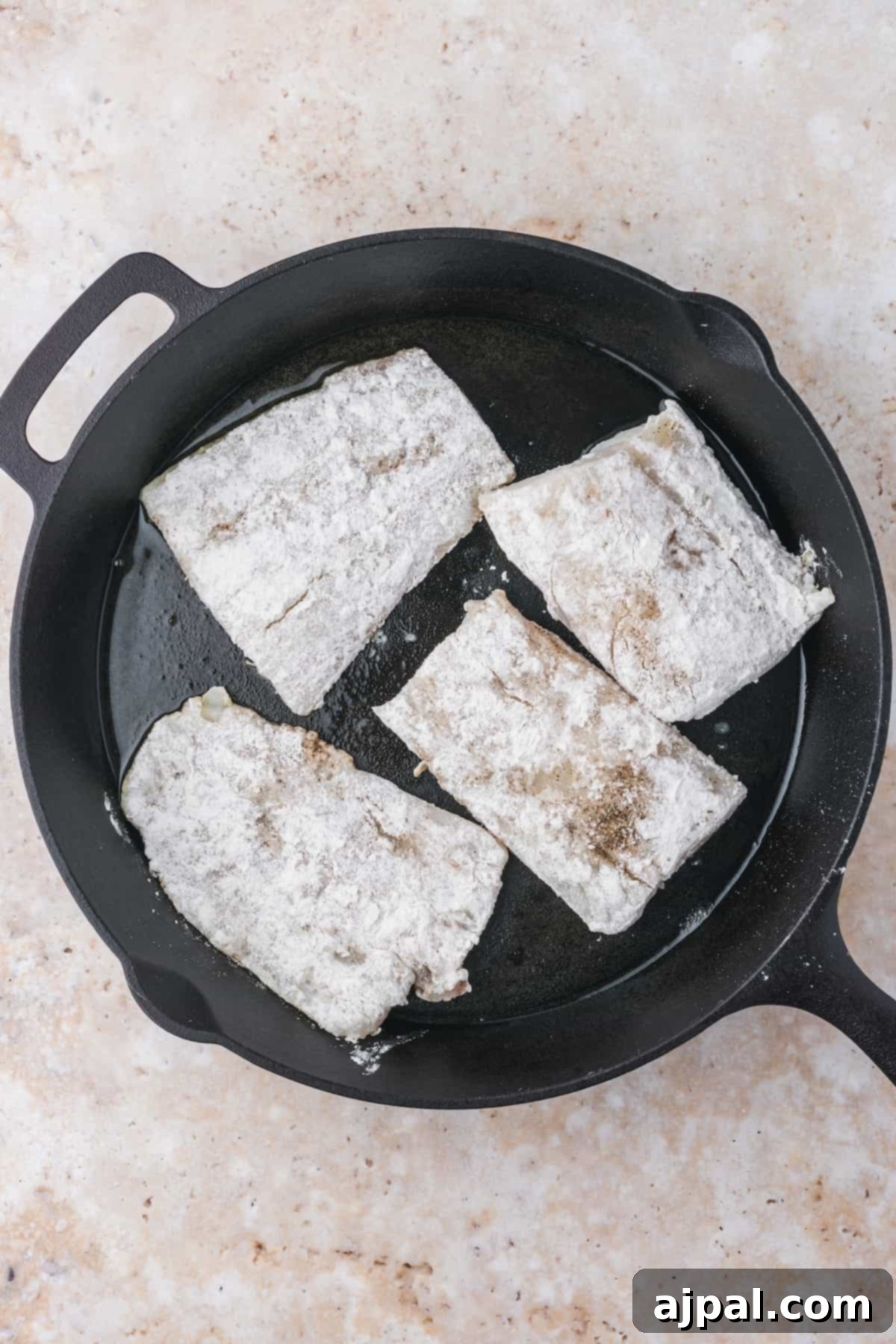 Golden Pan-Seared Cod 10 Two pan-seared cod fillets cooking in a cast iron skillet, showcasing the even browning and ideal cooking conditions for perfect fish.