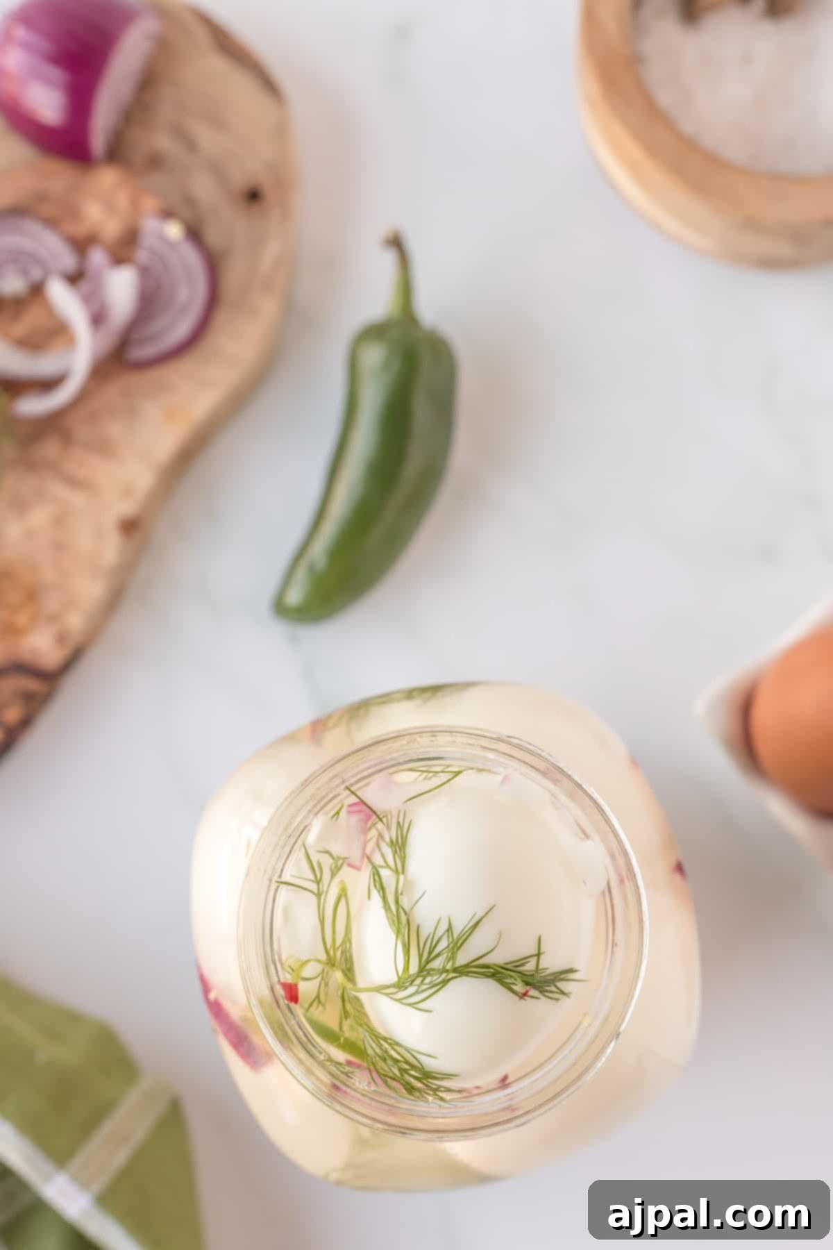 A jar with pickled eggs and spicy ingredients.