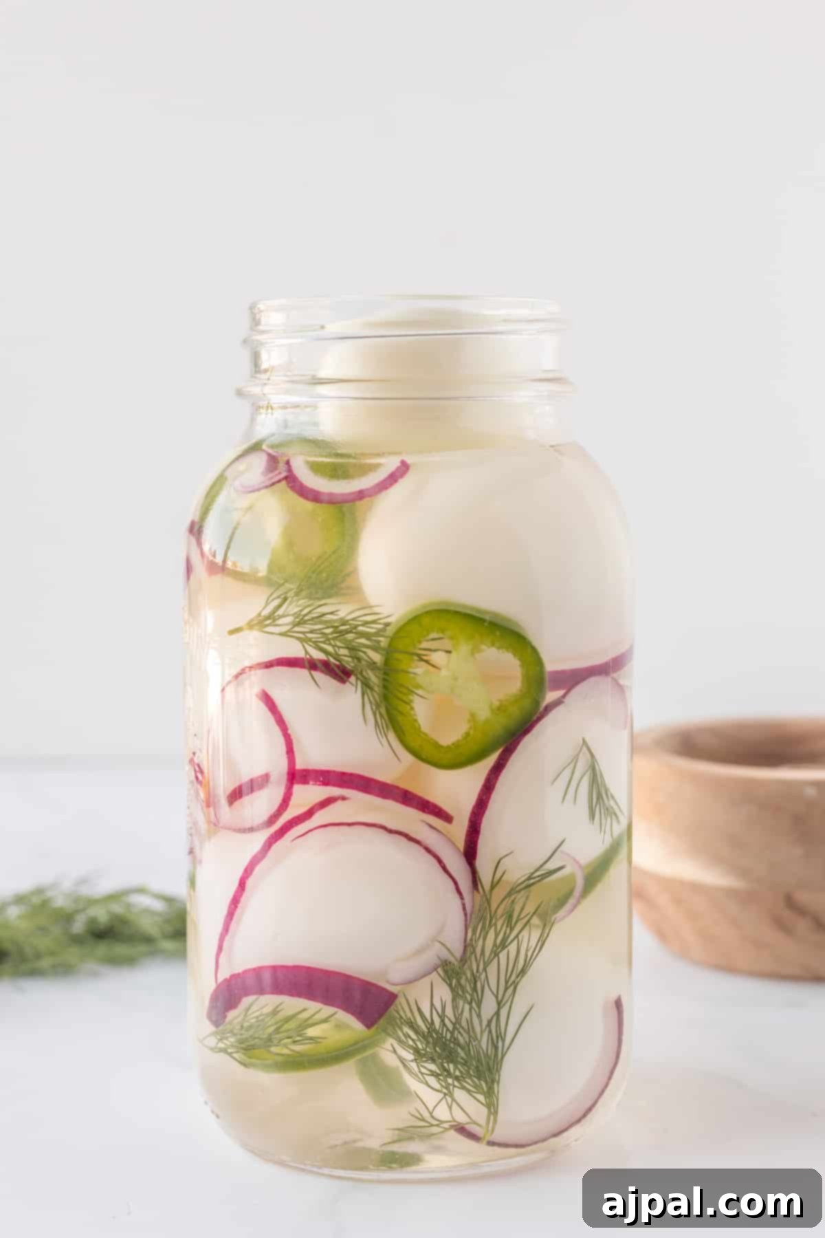 A jar of thinly sliced pickled red onions, a key ingredient for flavor and color.